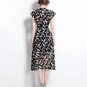 Women's black floral midi dress with sheer cap sleeves, featuring an elegant design suitable for summer, highlighting the neckline and waist.