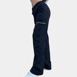 
A woman wearing black high-waist slim fit cargo pants featuring zipper pockets, casually standing with hands on hips.