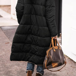 Women's black hooded oversized puffer coat in an urban street style, featuring long sleeves and a spacious fit.