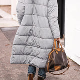 Women's black hooded oversized puffer coat styled for urban street fashion, showcasing its quilted design and relaxed fit with sleeves and waist details visible.