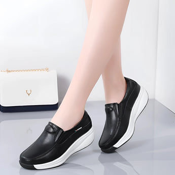 Women's black leather platform loafers on feet, showcasing the comfortable and stylish design.
