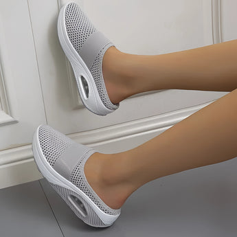 Women's gray mesh slip-on sneaker shown on a person's foot, highlighting its lightweight and breathable design.