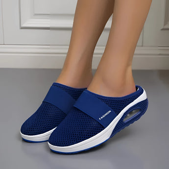 Women's blue mesh slip-on sneakers featuring a lightweight, breathable, and quick-drying design, shown on a person walking.