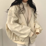 Women's black oversized bomber jacket worn by a model with sunglasses; the trendy puffer winter coat features a sleek design with a collar and long sleeves, paired over a dress shirt.
