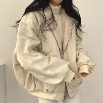 Women's black oversized bomber jacket worn by a model with sunglasses; the trendy puffer winter coat features a sleek design with a collar and long sleeves, paired over a dress shirt.