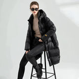 A woman wearing a black oversized hooded puffer coat, styled with sunglasses, showcasing a luxury winter fashion look.