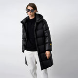 A man wearing a 3XL black oversized hooded puffer coat, featuring a high collar and long sleeves. The coat is styled as a luxury winter jacket, and the man accessorizes with sunglasses, emphasizing a fashionable look suitable for cold weather.