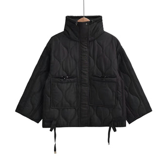 Woman wearing a black quilted puffer jacket, featuring a water-resistant and insulated design with a hood, suitable for cold weather.