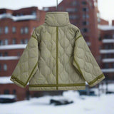 Women's black quilted puffer jacket with hood, featuring insulated and water-resistant fabric, shown in a snowy outdoor setting.