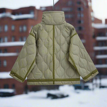 Women's black quilted puffer jacket with hood, featuring insulated and water-resistant fabric, shown in a snowy outdoor setting.