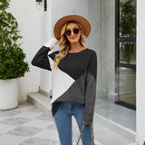 Women's black ribbed color block sweater featuring white cuffs, styled in a casual knitwear design, shown worn by a model accessorized with a fedora hat and sunglasses.