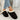 Women's black fuzzy lined shearling platform loafers being worn by a person dressed in jeans and a jacket, showcasing the footwear's stylish and cozy design.