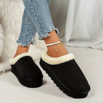 Women's black fuzzy lined shearling platform loafers being worn by a person dressed in jeans and a jacket, showcasing the footwear's stylish and cozy design.