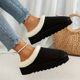 Women's black shearling fuzzy lined platform loafers worn by a person dressed in fashionable clothing.
