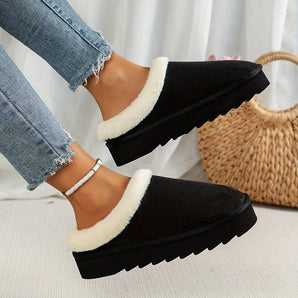 Women's black shearling fuzzy lined platform loafers worn by a person dressed in fashionable clothing.
