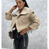 Women's black biker jacket with sherpa lining and faux fur collar, shown on a smiling model wearing beige shorts, highlighting the shoulder and sleeve details.