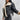 Women's black biker jacket featuring a sherpa-lined interior and a faux fur collar, shown in size large. The jacket has a classic biker design with long sleeves, tailored waist, and extends to the thigh. The outer material is predominantly black with contrasting textures.