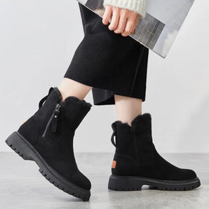 Women's black suede waterproof ankle boots with fur lining, worn by a person standing, showcasing the boots' cozy and stylish design ideal for winter wear.