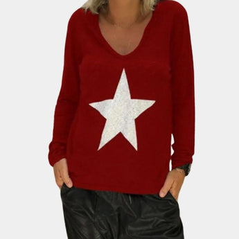 Women's black V-neck sequin star sweater with long sleeves, featuring a trendy pullover style. A person is wearing the sweater, paired with jeans, visible from shoulders to waist.