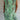 Women's green floral knee-length dress, featuring a lightweight fabric ideal for summer. The dress is styled as a tunic with a comfortable fit, showcasing a one-piece design. The image highlights the shoulder and arm features, and the green color is prominent throughout the garment.
