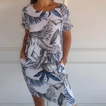 Women's blue floral knee-length dress featuring a lightweight summer tunic design, shown in size 5XL. The dress has short sleeves, a round neckline, and a flattering fit around the waist. The model is smiling, showcasing the dress's comfortable and stylish look.