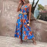 Women's blue floral wide-leg jumpsuit with a resort fashion style. The jumpsuit features a one-piece design and showcases a vibrant blue and azure floral pattern, highlighting the shoulders and neck area.