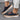 Women's black slip-on sneakers made from suede material, featuring a perforated design for breathability, suitable for comfortable walking.