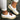 Women's blue suede slip-on shoes featuring a perforated upper with a colorful band, complemented by a white sole.