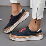 Women's blue suede slip-on shoe with a colorful perforated band and a white sole, designed for casual wear.