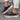 Women's blue suede slip-on shoe with a colorful perforated band and a white sole, designed for casual wear.