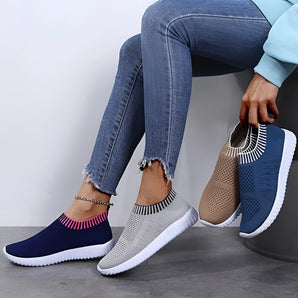 Blue women's breathable mesh slip-on sneakers in size 35, designed for summer wear with a lightweight and fashionable style. The image shows a model standing, highlighting the azure color of the shoes paired with trousers.