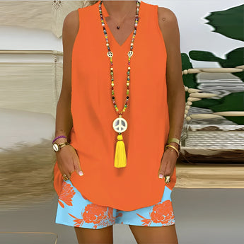 Women's bright orange V-neck top paired with floral shorts, designed for summer beachwear, shown in size 2XL. The top features short sleeves and the model is accessorizing with a necklace.