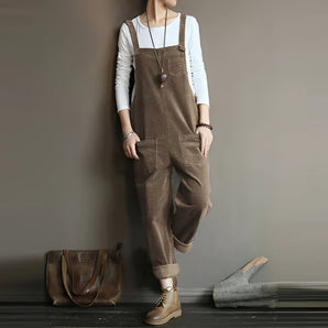 Women's vintage style brown corduroy overalls in a Cachi color, featuring adjustable straps and a relaxed fit. The overalls are styled with a collared shirt underneath, highlighting the shoulder and sleeve design. The fabric has a classic corduroy texture, and the overall outfit exudes a retro, casual aesthetic.