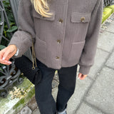 
A woman wearing an oversized brown corduroy jacket styled in a trendy casual urban fashion. The jacket features long sleeves and a relaxed fit, perfect for a comfortable yet stylish look.