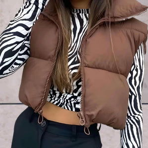 Women's brown hooded puffer vest in a stylish cropped design, showcasing a front view with a focus on shoulder and arm details, suitable for XXL size.