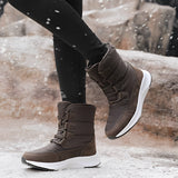 Women's brown waterproof insulated high-top snow boots being worn, showcasing their stylish design and knee-high coverage, set against an outdoor backdrop with trees.