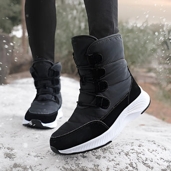 Women's brown waterproof insulated high-top snow boots worn by a person standing outdoors in the snow near a tree. The boots are designed for cold weather and provide style and protection.