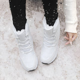 Women's brown waterproof insulated high-top snow boots worn by a person, showcasing the stylish design and cozy fit on the legs.