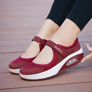 Women's burgundy mesh Mary Jane sneakers with comfortable air cushioning, shown worn on a model's feet, highlighting the footwear's design and fit.