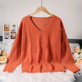 Burnt orange V-neck sweater made from soft knit fabric, featuring a relaxed fit with long sleeves, displayed on a clothes hanger.