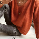 
A relaxed fit women's burnt orange V-neck sweater in a soft knit fabric, featuring long sleeves and designed in a pullover style. The sweater is displayed in a coral color variant and is available in size 2XL.