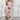 Woman wearing a pink blazer with tailored trousers, white trainers, posing confidently