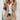 Woman wearing a brown blazer and tailored trousers with white trainers, showcasing a business casual outfit.