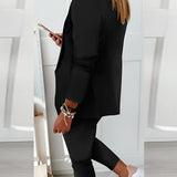 Woman wearing a black blazer, tailored trousers, and white trainers.