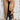 
A woman wearing a lightweight wool camel coat, styled as a casual chic outerwear piece, paired with jeans. The coat features long sleeves and extends to the waist. The model is accessorized with sunglasses and a neutral-toned outfit underneath the coat.