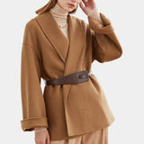 Women's oversized camel wool coat with minimalistic design, featuring a chic winter style. The coat is displayed on a standing mannequin, showcasing its shoulder and sleeve details. The beige wool fabric contributes to its elegant appearance.