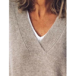 
A soft gray women's cashmere V-neck sweater with long sleeves, displayed on a wooden surface.
