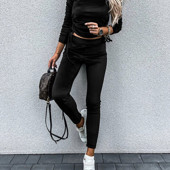 A woman wearing a cream tie-front top, high-waist trousers, and a black biker jacket in size XL, accessorized with sunglasses.