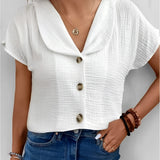 Women's white V-neck button-front short sleeve blouse worn with jeans.