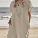 Woman wearing casual linen V-neck beach dress in apricot color, lightweight and short-sleeve, standing on a beach with the sky and water in the background, dress size 5XL.